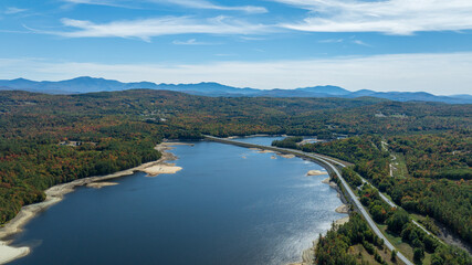 Aerial view of Moore Reservoir in Littleton, NH, surrounded by forested hills under a clear blue sky.