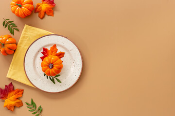 Festive Thanksgiving table setting with pumpkin in plate and napkin - autumn leaves decorated on...