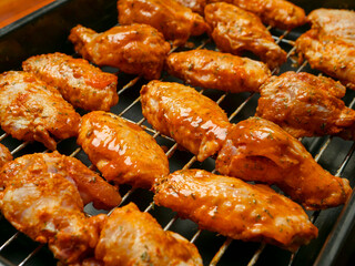 Cooking fresh chicken wings on an oven. The product is covered in red Asian style sauce and ready for cooking in high temperature. Party finger snack food.