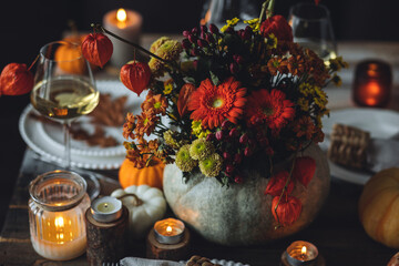 Fall composition. Orange pumpkins, flowers and candles on wooden table. Family elegant Thanksgiving or halloween dinner. Cozy autumn concept, simple handmade decoration, countryside style, wine