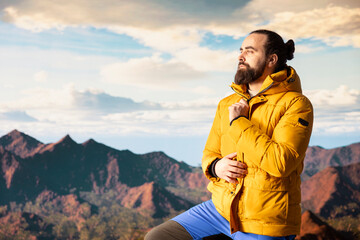 Naklejka premium Male trekker takes in the breathtaking mountain landscape on rocks, enjoying the scenic background, crisp air and rugged peaks. Excitement of discovering new horizons for wellbeing.
