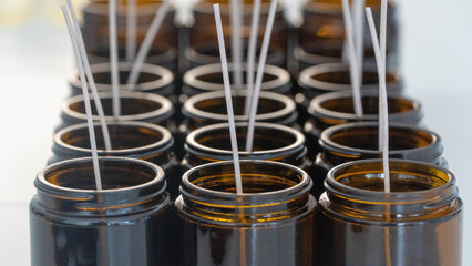 Rows of handcrafted candles with wicks in amber glass jars, ready for pouring.