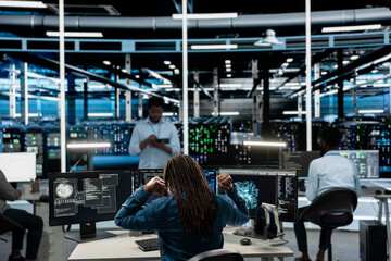 Fatigued data center worker stretching at desk, using machine learning algorithms to analyze datasets. Tired server farm engineer relaxing muscles, using AI to recognize data patterns