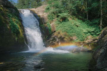 Cascading waterfalls flow naturally down a green mountain stream through a rocky forest landscape