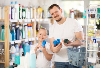 Obraz premium Boy and father in process of choosing garbage bags, looking at packages, reading labels on packages. Family shopping in household department, pick up household chemistry during store routine buying