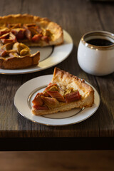 freshly baked Rhubarb pie on a dark wooden table. piece of a hommade bakery with coffee in a morning` lightning