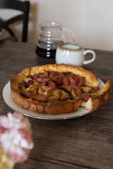 freshly baked Rhubarb pie on a dark wooden table. piece of a hommade bakery with coffee in a morning` lightning