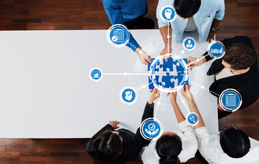 A diverse team collaborates in a business meeting, engaging with technology and a globe puzzle concept. This image symbolizes teamwork, innovation, and strategic planning. Amity