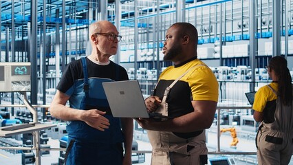 Smart factory senior engineer teaching new trainee to manage robotic arms. Industry 4.0 industrial...