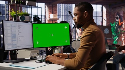 Programmer coding in startup office using green screen PC, building scalable solutions for...