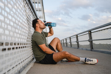 Male athlete resting and hydrating during workout