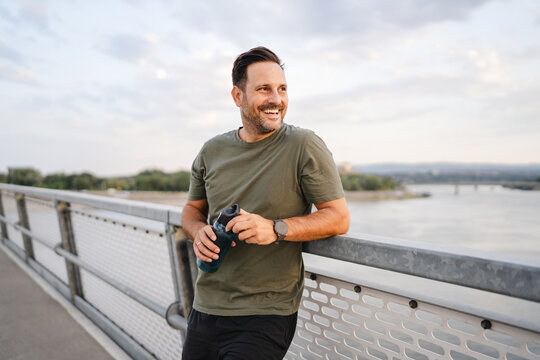 Man smiling taking a hydration break on bridge