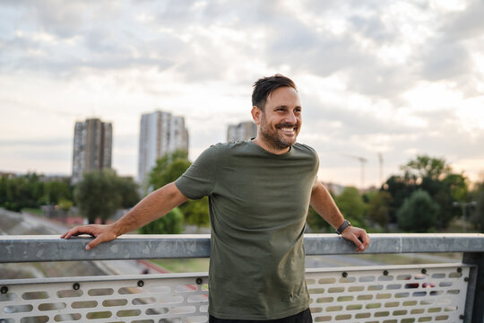 Happy man smiling on city bridge enjoying urban view - Powered by Adobe