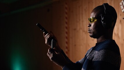 Portrait of happy shooting range customer reloading pistol, shooting targets, having fun. Close up...