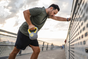 Man doing bent over kettle bell row exercise outdoor
