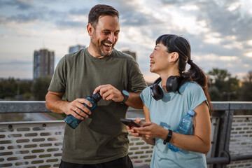 Healthy multiracial couple laughing after outdoor workout