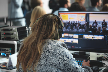 Woman wearing headphones sits in front of computer monitor. She's working on  project or...