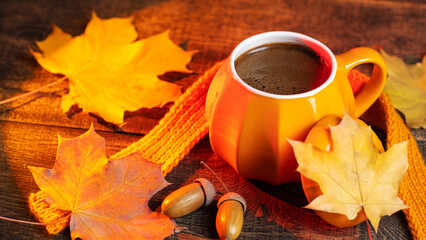 Hot cup of coffee on wooden table with maple colorful leaves