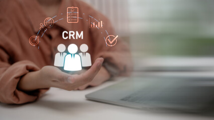 Hand presenting CRM icons with people, chart, target, checklist, and network, symbolizing customer relationship management system in modern digital business strategy.