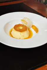 flan in a round plate with caramel and gourmet decoration