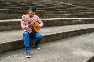 Man playing mandolin on concrete steps outdoors