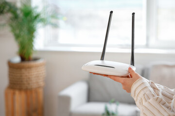 Woman with modern wi-fi router at home, closeup