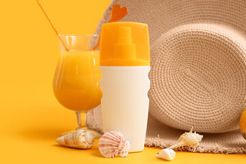 Bottle of sunscreen cream, glass of juice, seashells and hat on color background