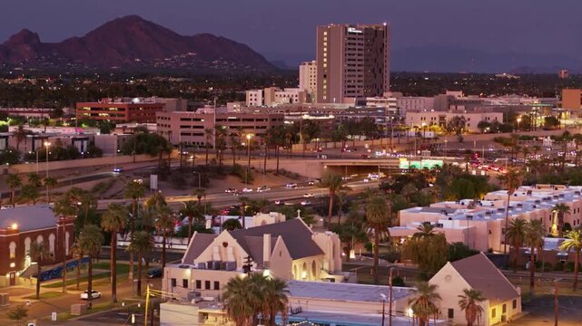 The cityscape shows the city lights at night with mountains in the background
