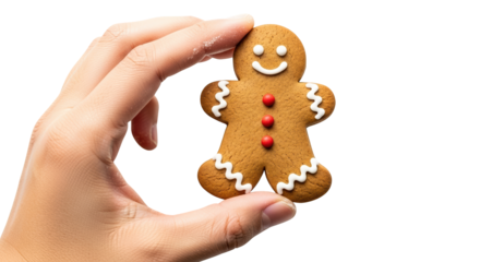 A hand holds a gingerbread man cookie decorated with white icing and red candies, isolated on transparent background