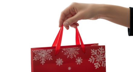 A hand holding a red gift bag with white snowflakes, isolated on transparent background