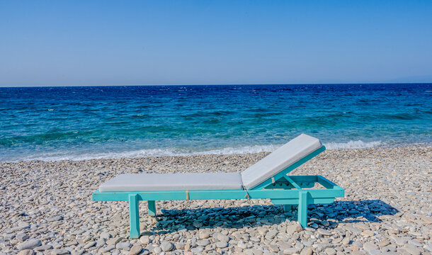 Beach chair on a peeble beach in greece, turquoise water in summer
