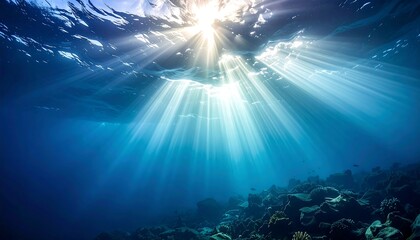 Sun rays piercing the surface illuminate a dark, deep ocean, shining onto a rocky seabed in vivid shades of blue
