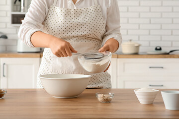 Woman preparing traditional cinnamon rolls in kitchen