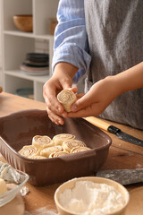 Woman preparing traditional cinnamon rolls in kitchen