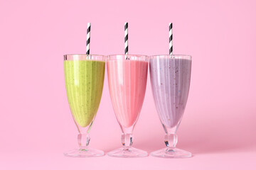 Glasses of different fresh smoothie on pink background