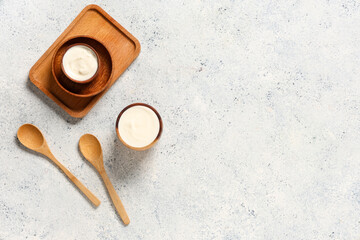 Wooden bowls of tasty yogurt on white background