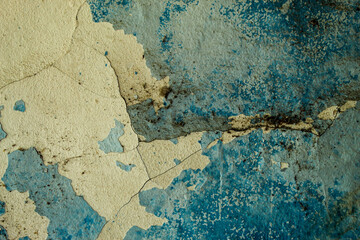 wall texture with peeling and cracked blue paint, revealing a layer of gray cement plaster