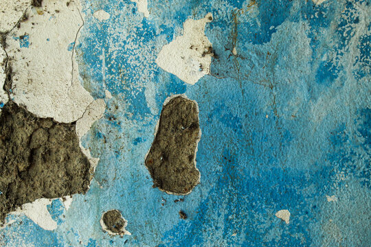 wall texture with peeling and cracked blue paint, revealing a layer of gray cement plaster - Powered by Adobe