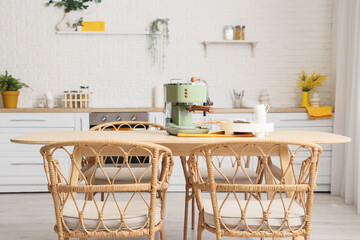 Modern coffee machine with cups and beans on table in kitchen