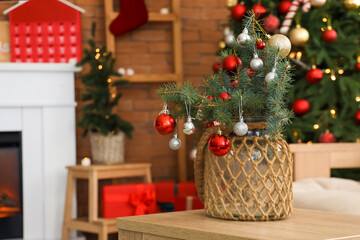 Small Christmas tree with baubles on coffee table in festive living room, closeup