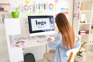 Female graphic designer working at table in office, back view