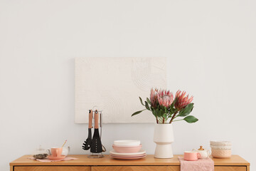 Kitchen utensils and vase with protea flowers on table against white background. Closeup