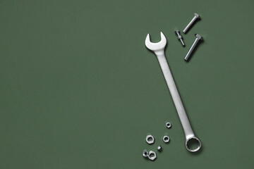 Wrench with tap bolts and chrome nuts on green background