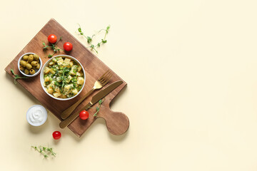 Bowl of tasty potato salad with micro green and olives on yellow background