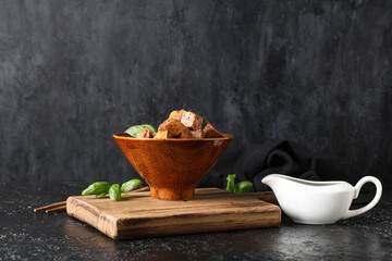 Bowl with pieces of fried tofu cheese and basil on black background
