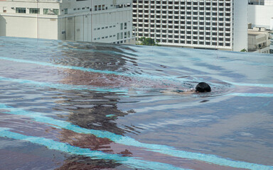 Unrecognizable person Swimming in Rooftop Pool with City View