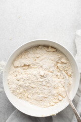 Overhead view of cold butter flour and sugar being mixed to make tart dough in a mixing bowl, process of making tart and pie shell or crust