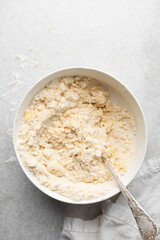 Overhead view of tart and pie crust dough being mixed in a mixing bowl, process of making tart
