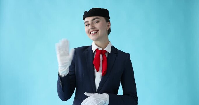 Beautiful stewardess waving on light blue background