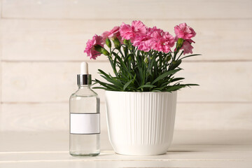 Bottle of plant fertilizer on white wooden background
